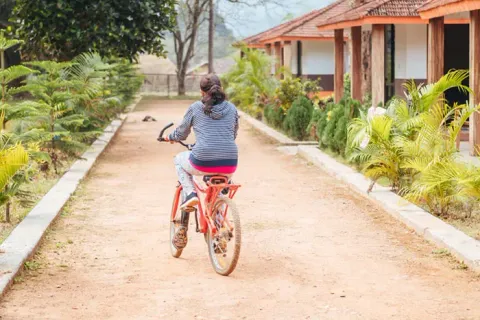 Visitor cycling through a nature camp pathway
