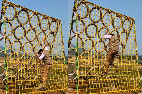 Visitors climbing an outdoor rope net obstacle